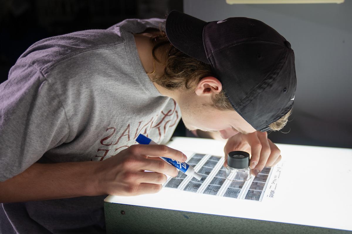 Student looks closely at negatives on a lit table